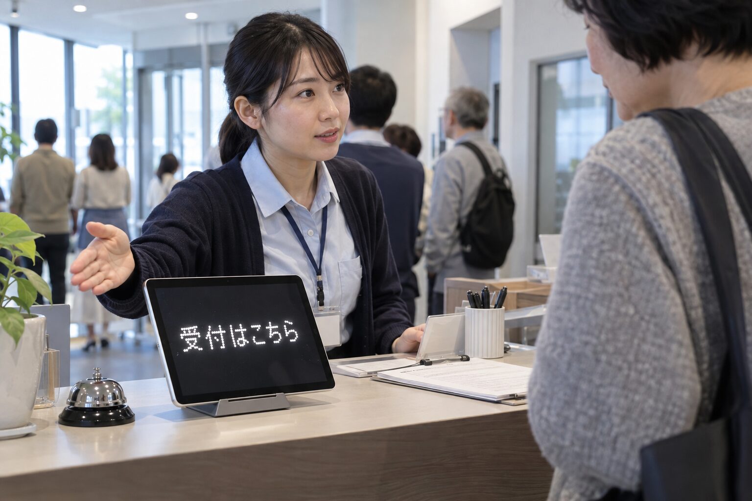 受付で案内するスタッフと受付はこちらを示すiPad
